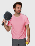 Man wearing coral Dink Performance Tee by MUEV holding pickleball paddle and ball for pickleball clothing